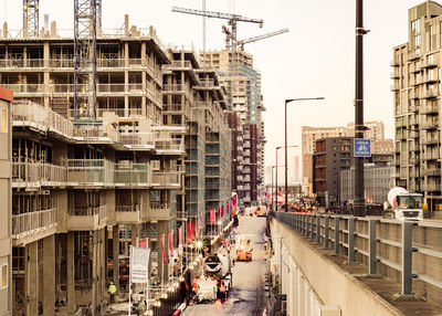 Cars on road by buildings against sky in city