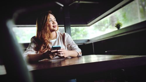 Woman using mobile phone while sitting on table