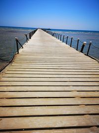 Wooden pier on sea against clear sky