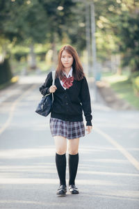 Portrait of a young woman standing on road