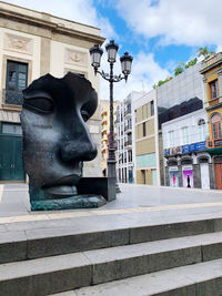 Statue against building in city against sky