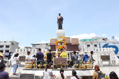 People outside temple against sky