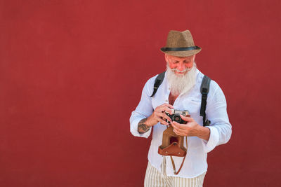 Full length of man wearing hat against red background