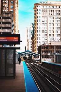 Railroad tracks amidst buildings in city against sky