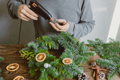 The hands of a male florist makes a new year's drenching from fresh spruce branches, cones 