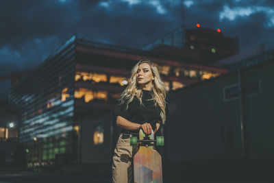 Woman standing against illuminated city at night