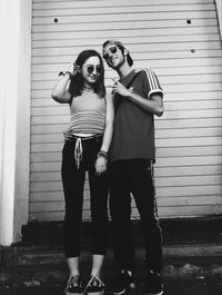 Portrait of young couple standing against wall