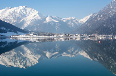 Scenic view of lake by snowcapped mountains against sky