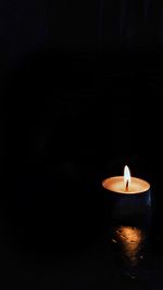 Lit candle in dark room