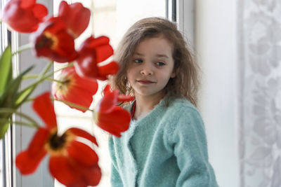 Close-up of girl standing by red flowers