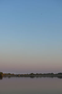 Scenic view of lake against clear sky during sunset