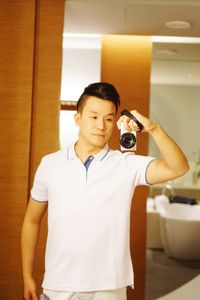 Mid adult man photographing with camera while standing at home