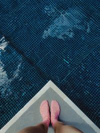 Low section of woman standing by swimming pool