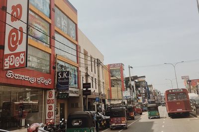 Vehicles on road against sky in city