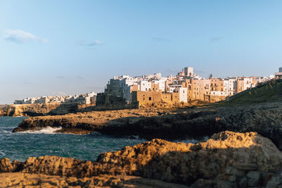 Buildings by sea against clear blue sky