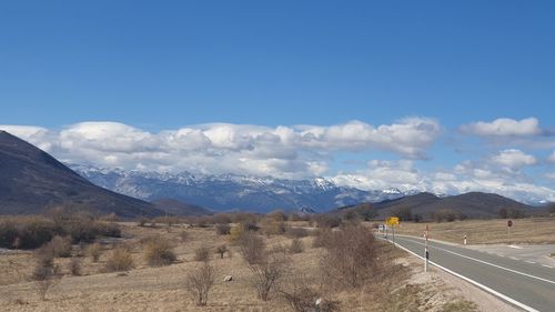 Road leading towards mountains against blue sky