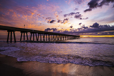 Pier over sea against sky during sunset