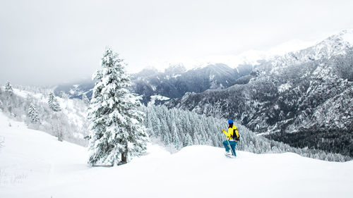 Rear view of person on snowcapped mountain against sky