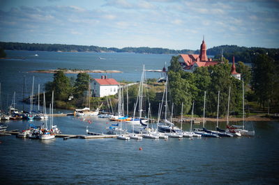 Sailboats moored in harbor by buildings against sky