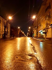 Illuminated road amidst buildings in city at night