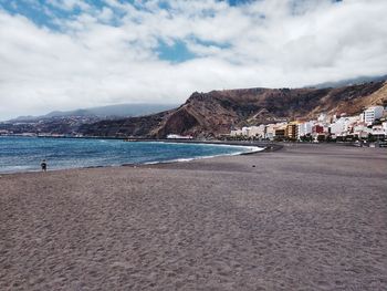 Scenic view of beach by city against sky