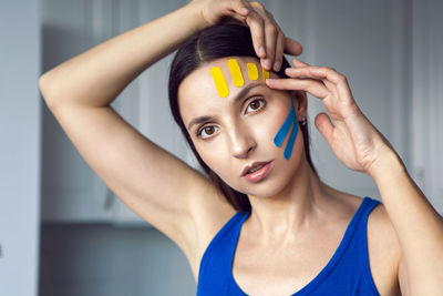 Portrait of a young woman with pasted konesiotape for rejuvenation and face tightening