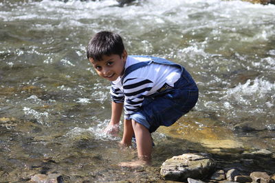 Rear view of boy on rock in sea