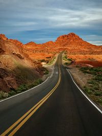 Road leading towards mountains against sky