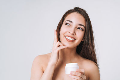 Portrait of beautiful young woman drinking water against white background