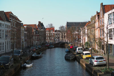 Boats in canal amidst buildings in city against clear sky