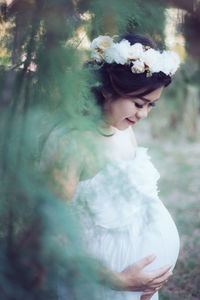 Pregnant woman in white dress holding belly