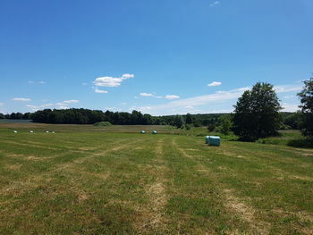 Covered hay bales on field against sky