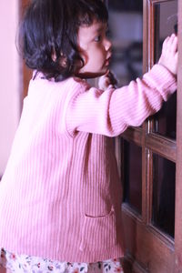 Girl looking away while standing on pink indoors