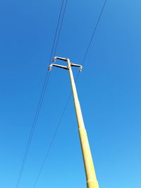 Low angle view of electricity pylon against blue sky