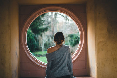 Rear view of woman standing against window