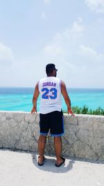 Rear view of man standing on beach against sky