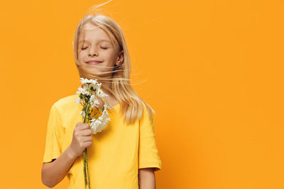 Girl smelling flowers against yellow background