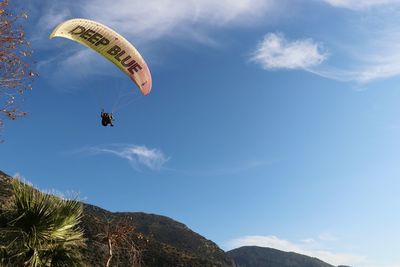 Low angle view of person paragliding against sky
