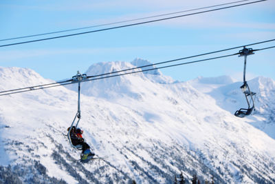 Low angle view of overhead cable car against snowcapped mountains