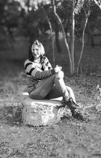 Young woman sitting on tree