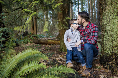 Young couple kissing on plants against trees