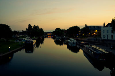 Boats moored in river at sunset