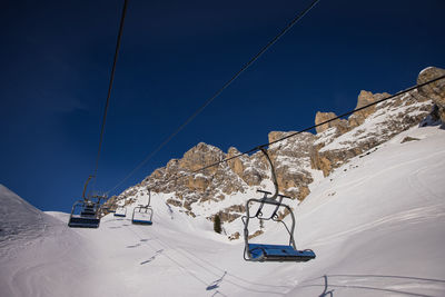 Ski lift over snowcapped mountains against sky