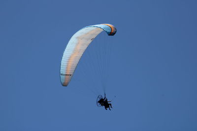 Low angle view of person paragliding against clear blue sky