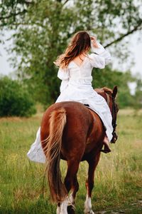 Young woman riding horse on field