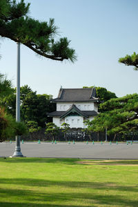 Houses and trees on field against clear sky