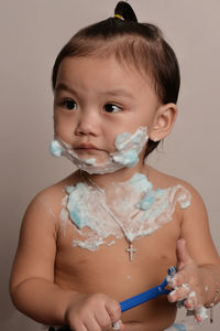 Close-up of baby boy playing with shaving cream and razor at home