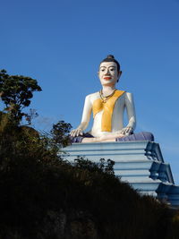 Low angle view of buddhist statue against blue sky in kampot, southern cambodia. 