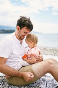 Father with baby on beach against sea