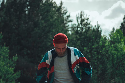 Young man standing against trees